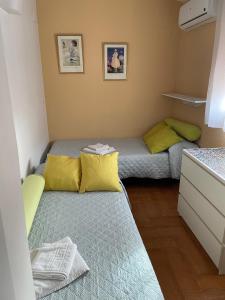 塞维利亚Familia anfitriona acoge的小房间设有两张带黄色枕头的床