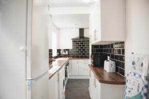 莱斯特Leicester Park House的厨房配有白色橱柜和黑色瓷砖