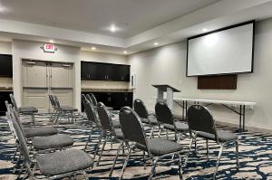 拉斐特Comfort Suites Oil Center的一个带椅子和投影屏幕的会议室
