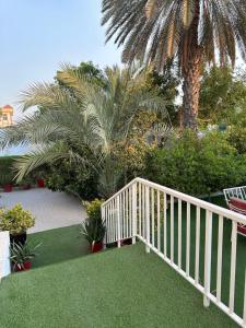 沙迦Al Ramla, Na’eem Bin Masoud St#8, Villa#10的白色的木楼梯通往棕榈树庭院