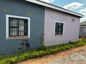 MzuzuChaya accommodation B&B and self catering的蓝色和粉红色的房子,设有2个窗户