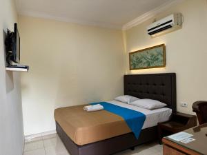 井里汶Hotel Priangan的一间卧室配有一张带蓝色毯子的床