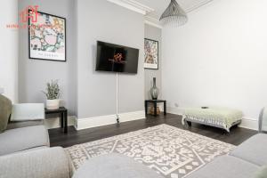 利物浦Spacious 5-Bedroom Oasis with Games Room-Liverpool的客厅配有沙发和墙上的电视