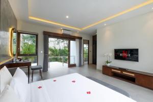 努沙杜瓦Taman Dharmawangsa Suites的一间卧室配有一张床、一张书桌和一台电视。