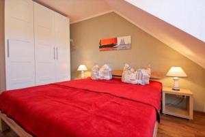 奥斯赛拜-屈隆斯博恩Strandschloesschen-Haus-II-WE-21-9820的一间卧室配有一张红色的床和两盏灯