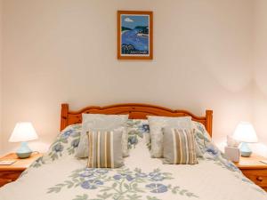 霍普湾4 Bed in Hope Cove 90027的一间卧室配有一张带两盏灯的床,墙上挂着一张照片
