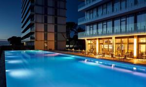 科布列季Miramare Magnetic Beach Hotel的一座游泳池,在晚上在建筑物前