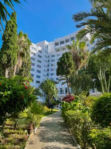 丹吉尔肯兹索拉祖尔酒店的一座白色的大建筑,种植了棕榈树,设有走道
