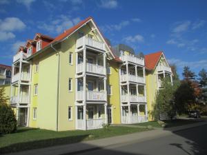 奥斯赛拜-屈隆斯博恩Strandschloesschen-Haus-II-WE-18-9723的大型黄色公寓大楼设有白色阳台
