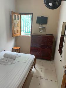 邦热苏斯-达拉帕casa pedacinho do morro的一间卧室配有一张床、一个梳妆台和一扇窗户。