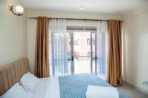 坎帕拉FG Homestay, Kampala Muyenga-Bukasa的一间卧室设有一张床和一个大窗户