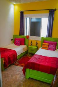 Tamraght Ou FellaDar Sultana Guesthouse Surf Morocco的黄色和红色客房的两张床