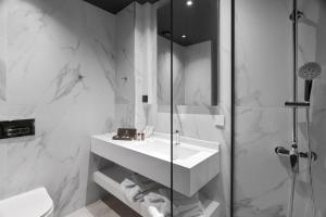 沃洛斯Azur Hotel Volos的白色的浴室设有水槽和淋浴。