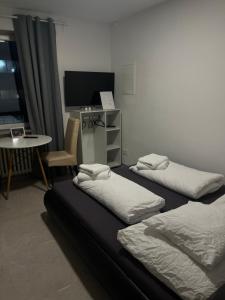 科隆House Cologne的配有两张床铺、一张桌子和一台电视机的客房