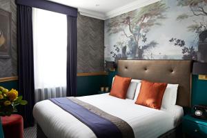 伦敦The Portico Hotel的一间卧室配有一张带橙色枕头的大床