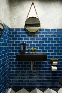 伦敦The Portico Hotel的蓝色瓷砖浴室设有黑色水槽和镜子