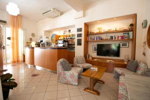 里米尼Hotel Villa Gioiosa的客厅配有电视、椅子和桌子
