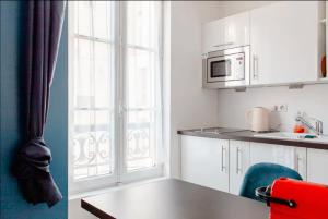 凡尔赛Le Studio Versaillais的厨房配有白色橱柜、桌子和微波炉