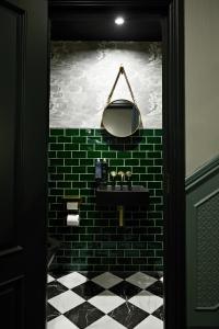 伦敦The Portico Hotel的浴室设有黑色水槽和绿色砖墙