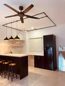 汝来Nilai Youth City Residence的厨房配有吊扇和黑冰箱。
