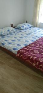 科钦Jestine Homestay的一间卧室配有一张带紫色和蓝色棉被的床