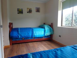埃尔基斯科Cabanas Piedras Preciosas的一间卧室配有一张带蓝色床单的床和一扇窗户。