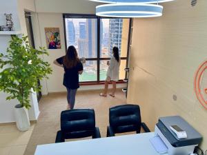 迪拜Berloga Capsule JBR的两个站在窗外的办公室里的妇女