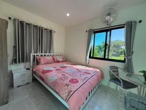 慕斯Pada Guesthouse Khaoyai的一间卧室配有一张床、一张书桌和一个窗户。