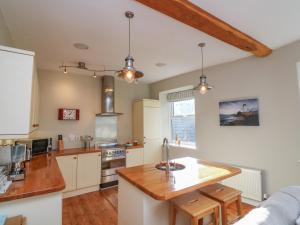 达特茅斯1 Bailey's Cottage的厨房配有白色橱柜和木制台面
