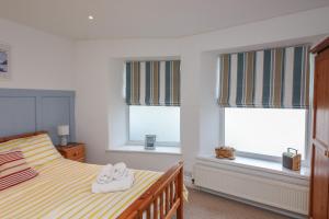 达特茅斯1 Bailey's Cottage的一间卧室配有床和两个带毛巾的窗户。