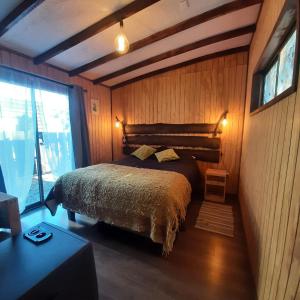 PutaendoRefugio Zen Spa的卧室配有一张床铺,位于带木墙的房间内