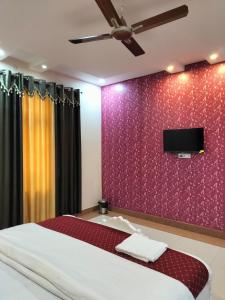 瓦拉纳西Shree Nanda Guest House的一间卧室配有一张床,墙上配有电视