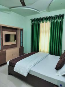 瓦拉纳西Shree Nanda Guest House的一间卧室配有一张带绿色窗帘的床和电视。