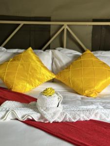 MochudiSABI Escapes的一张带两个黄色枕头和毛巾的床