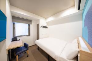 东京Hop Inn Tokyo Iidabashi的客房设有床、书桌和窗户。