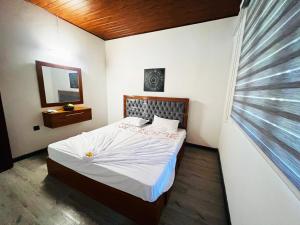 阿鲁特伽马Nature Bliss Villa的一间卧室配有一张带白色床单的床和一扇窗户。