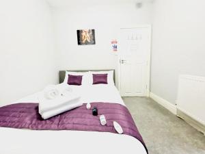 布莱克浦Blackpool - Seaside的一间卧室配有一张大床,提供紫色床单和毛巾