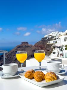 菲罗斯特法尼圣托里尼遐想酒店的一张桌子,上面放着两杯橙汁和糕点