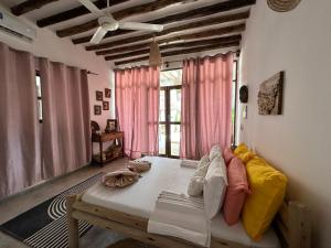 江比阿Olamanga Beach Villa的客房设有床和带粉红色窗帘的窗户。