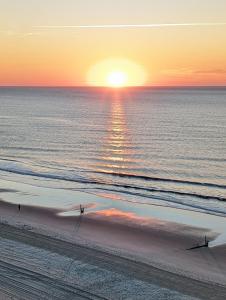 默特尔比奇Oceanfront Get Away的日落时在海滩上散步的人