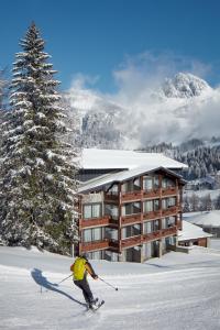 索内纳尔佩·纳斯费尔德Hotel Wulfenia 4S - Adults Only的滑雪者在小屋前的雪中滑雪