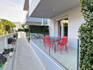利多迪耶索罗Dainese Apartments, Casa Miriam的阳台的天井配有红色椅子和桌子