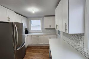 温尼伯St B. Living的厨房配有白色橱柜和不锈钢冰箱