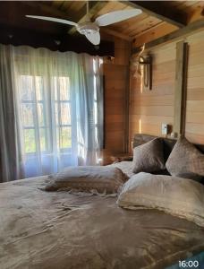 坎普阿莱格里Chalé Cafofo的卧室在窗户前配有一张大床