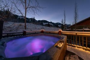 戈尔登葱郁山间度假屋的雪中带紫色灯的热水浴池
