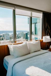 温哥华蓝色地平线酒店的一张位于带大窗户的房间内的床铺
