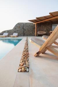 圣爱奥尼斯米科诺斯Birdhouse Private Luxury Suite的游泳池旁的游泳池,有一排岩石