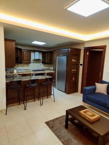 安曼Dair Ghbar - Amman Apartment的一间带蓝色沙发的客厅和一间厨房