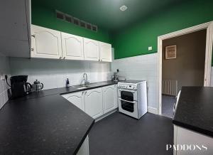 塔维斯托克Impressive 3 bedroom apartment, Tavistock, DEVON.的厨房配有白色橱柜和绿色墙壁