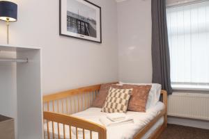 赫尔Cosy 3 bed home with garden - near to uni, restaurants & bars的窗户房间里一张婴儿床